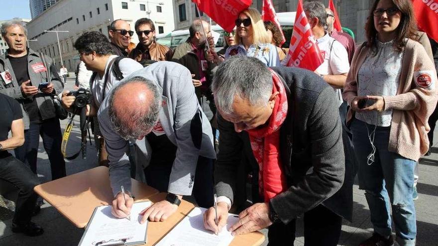 Los líderes de CCOO y UGT firman en el inicio de la campaña de recogida de firmas ante el Congreso.