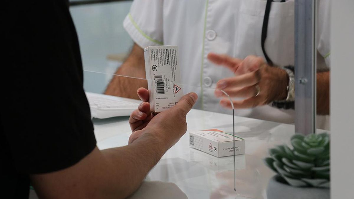 Mostrador de una farmacia con una mampara de protección.