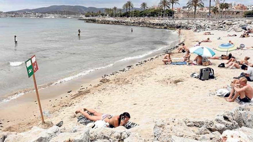 Bañistas en la Costa del Gas. A la izquierda, el cartel que recomienda no bañarse en esas aguas.