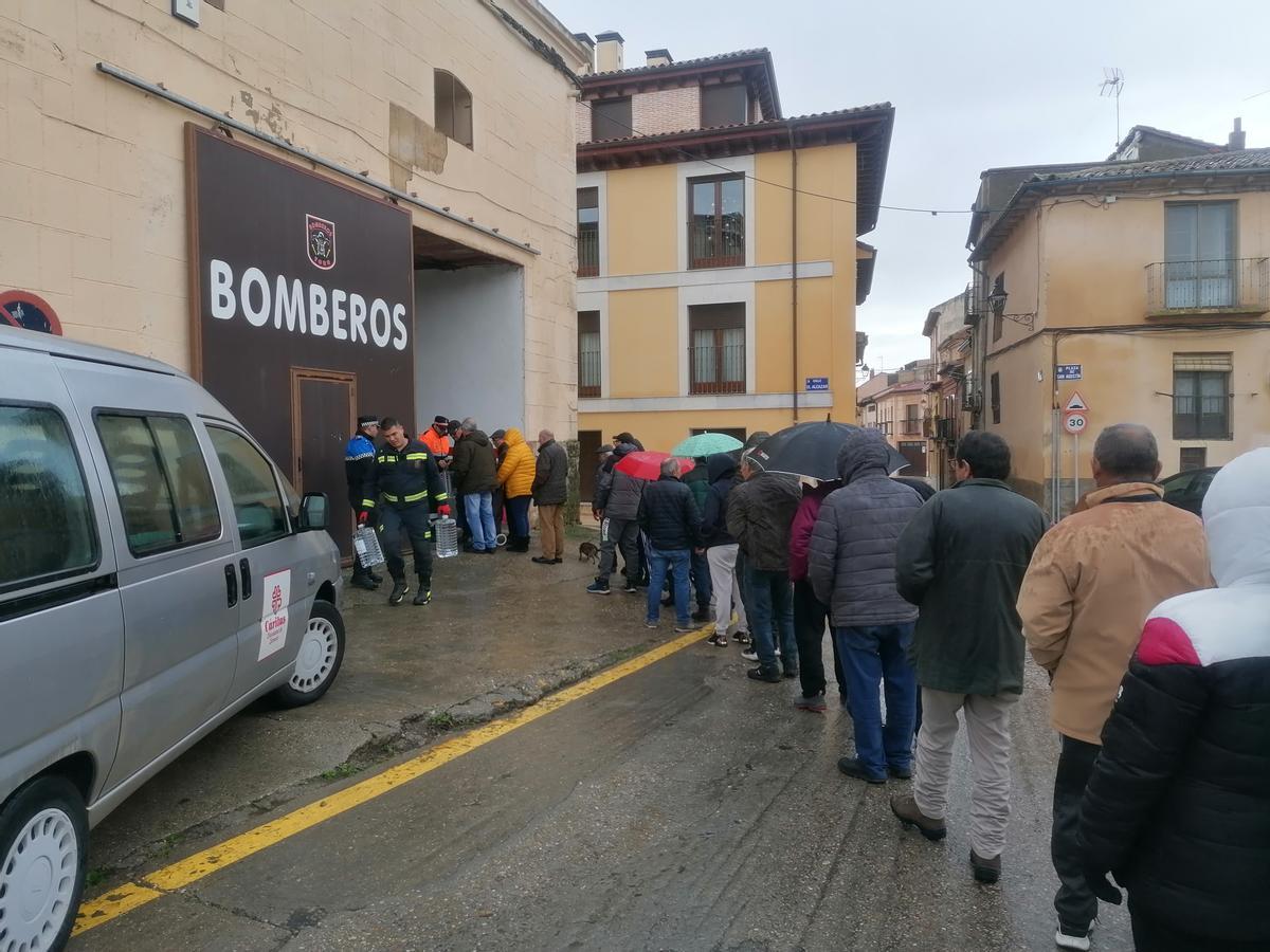 Vecinos esperan en el entorno del Parque de Bomberos para retirar una garrafa de agua