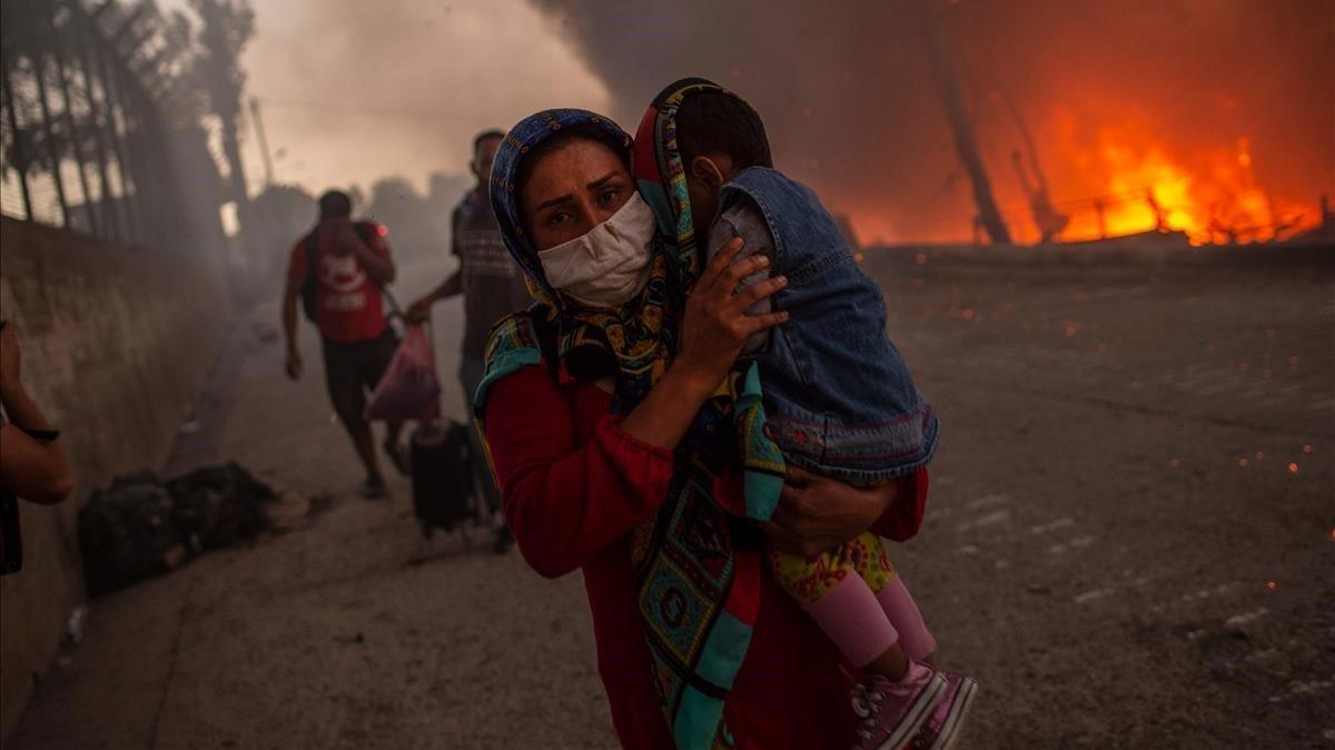 Una madre huyo con su hijos de las llamas en el campo de refugiados de Moria, en Lesbos.