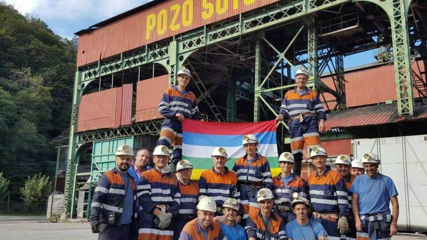 Miembros del Codis y mineros posan ante el pozo Sotón con la bandera del Sella.