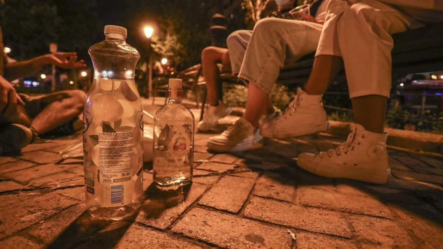 Unos jóvenes en un parque de València conversan y beben alcohol durante un botellón. | PACO CALABUIG