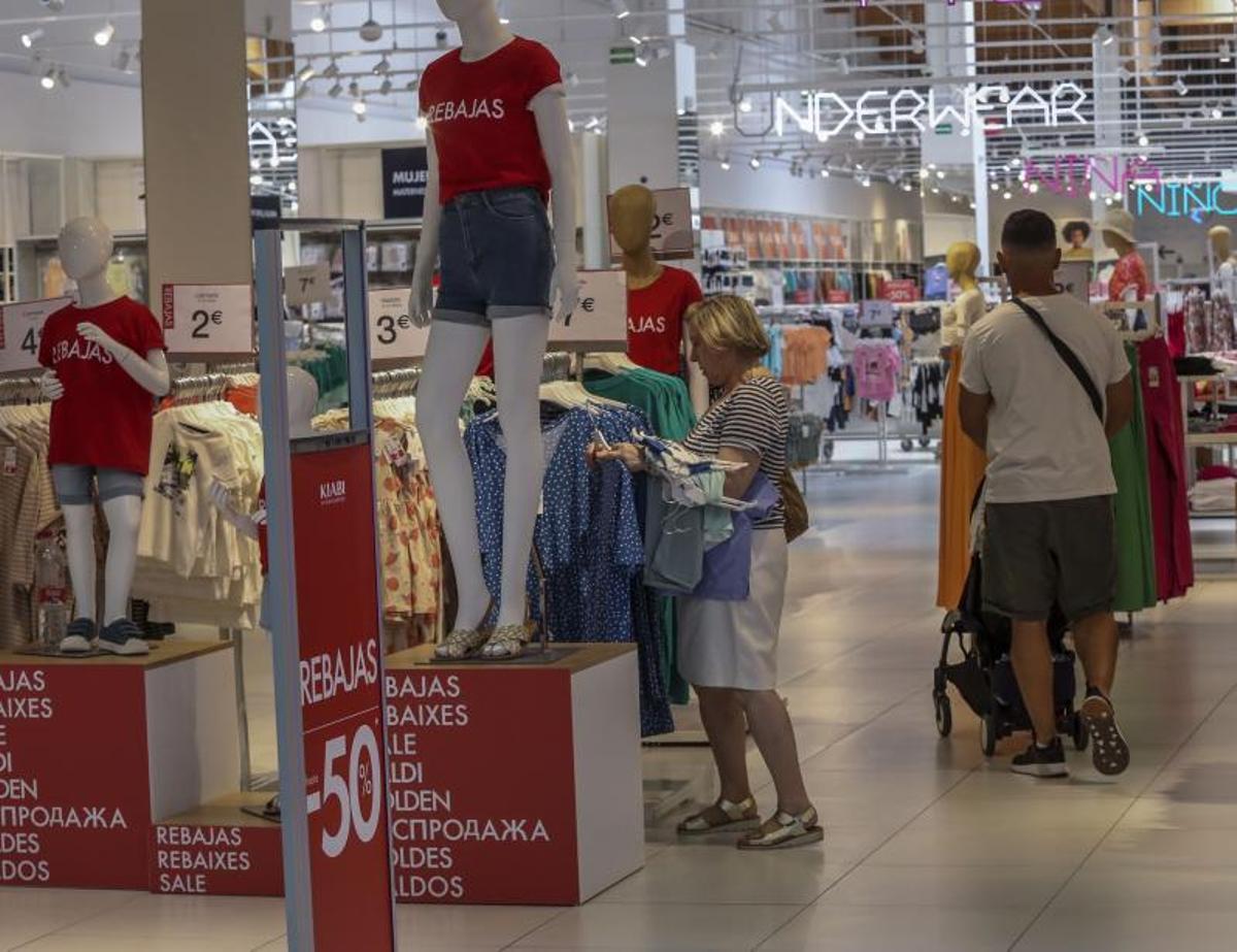 Una clienta de un comercio del centro comercial l’Aljub de Elche mira varios artículos rebajados en hasta un 50%.  | ANTONIO AMORÓS