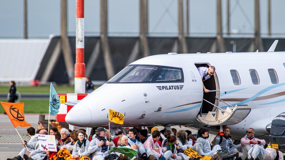 Activistas climáticos bajo un avión privado en el Aeropuerto de Ámsterdam-Schiphol