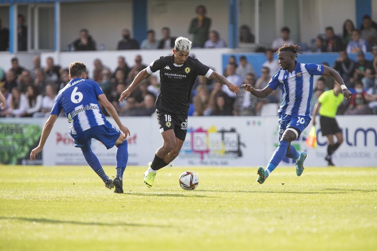 César Moreno trata de colarse entre dos rivales del Águilas, Quim Araujo (i) y Loussoukou (d), durante la visita en Liga del Hércules al estadio El Rubial.