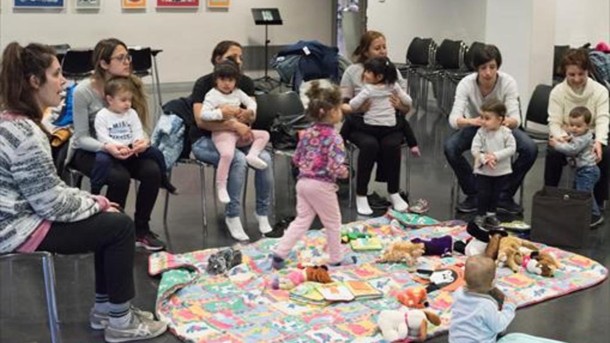 Madres con sus niños pequeños en una de las sesiones de juegos de falda que coordina Rosa Ferrer en la biblioteca Zona Nord.