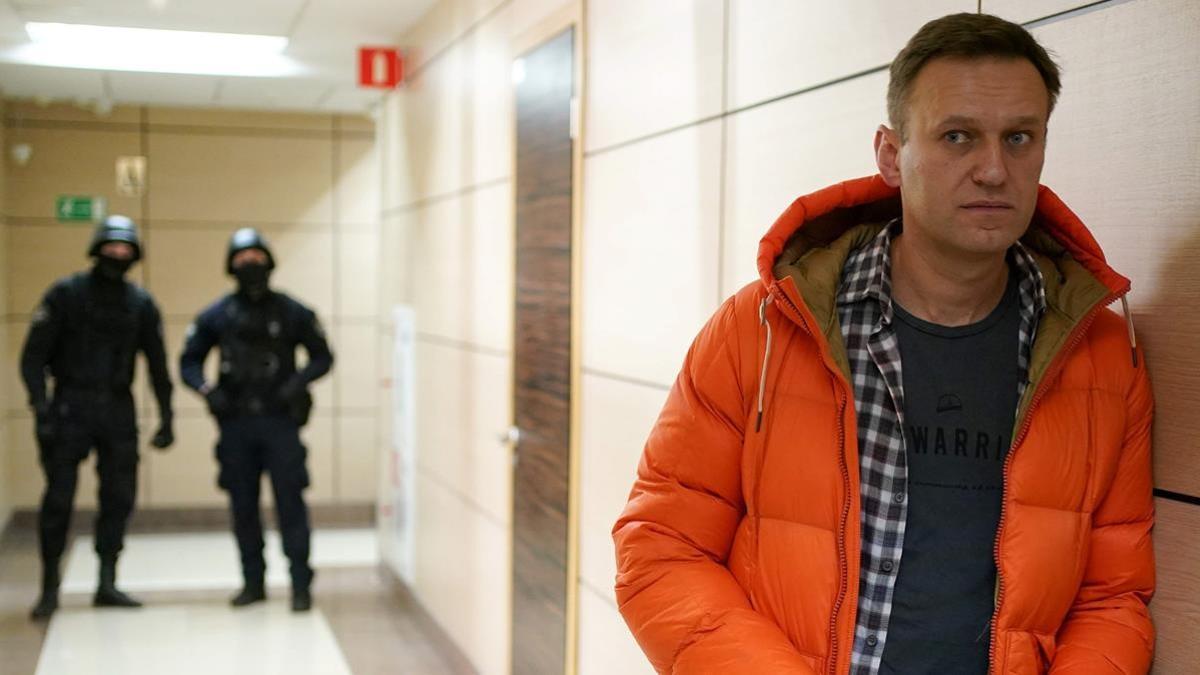 (FILES) In this file photo taken on December 26  2019 Russian opposition leader Alexei Navalny stands near law enforcement agents in a hallway of a business centre  which houses the office of his Anti-Corruption Foundation (FBK)  in Moscow  - Russian opposition leader Alexei Navalny said on December 21  2020 he had tricked a security agent into admitting the Federal Security Service (FSB) sought to kill him this summer and placed poison in his underwear  (Photo by Dimitar DILKOFF   AFP)