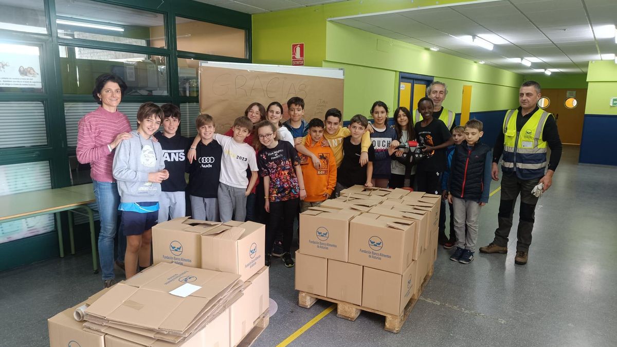 Por la izquierda, María Milán, profesora de Religión, con una representación de alumnos de sexto de Primaria, hacen la entrega a los representantes de la Fundación Banco de Alimentos de Asturias.