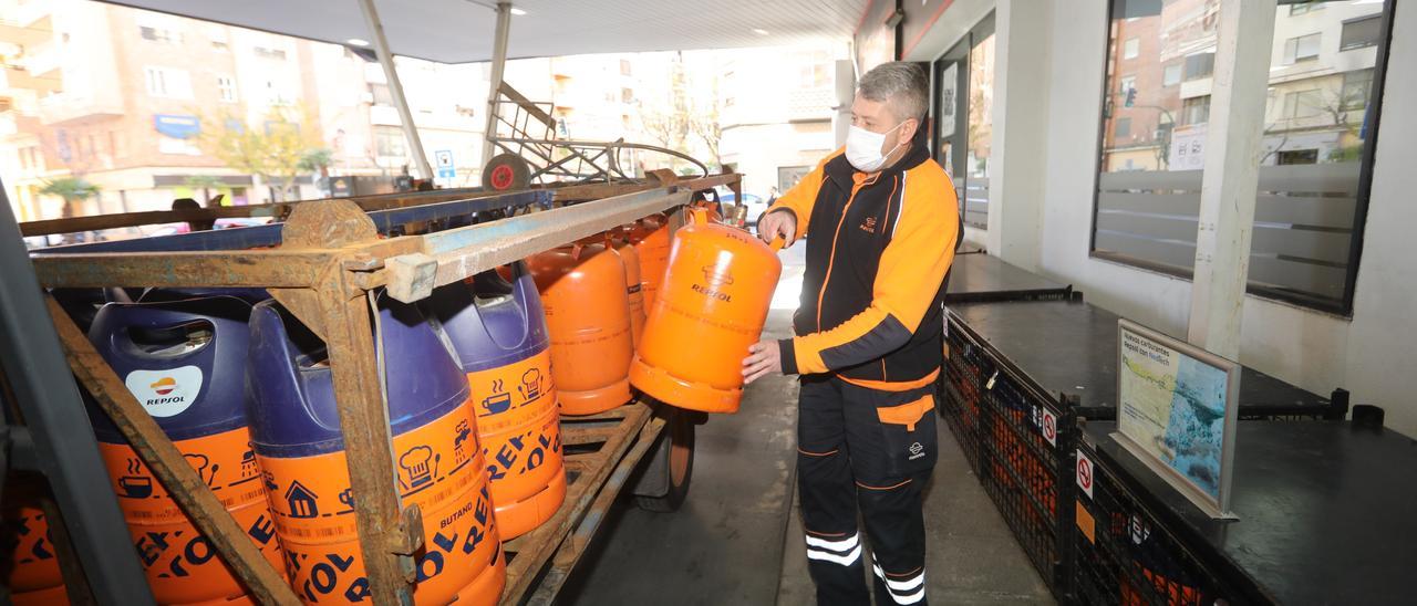 Un trabajador de una empresa energética descarta un camión de bombonas de butano en una estación se servicio de Castelló.