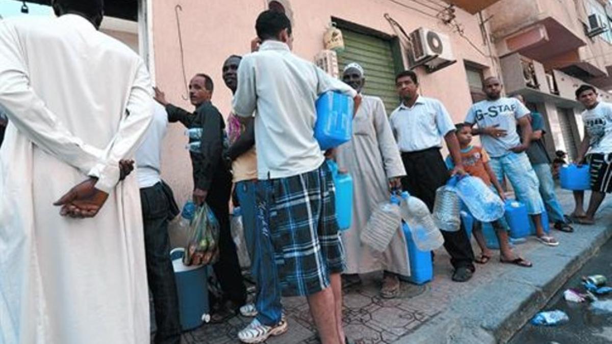 Ciudadanos de Trípoli hacen cola para conseguir agua en el distrito de Masira Kobra, ayer.