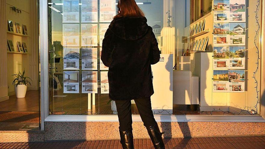 Una mujer observa el escaparate de una inmobiliaria.