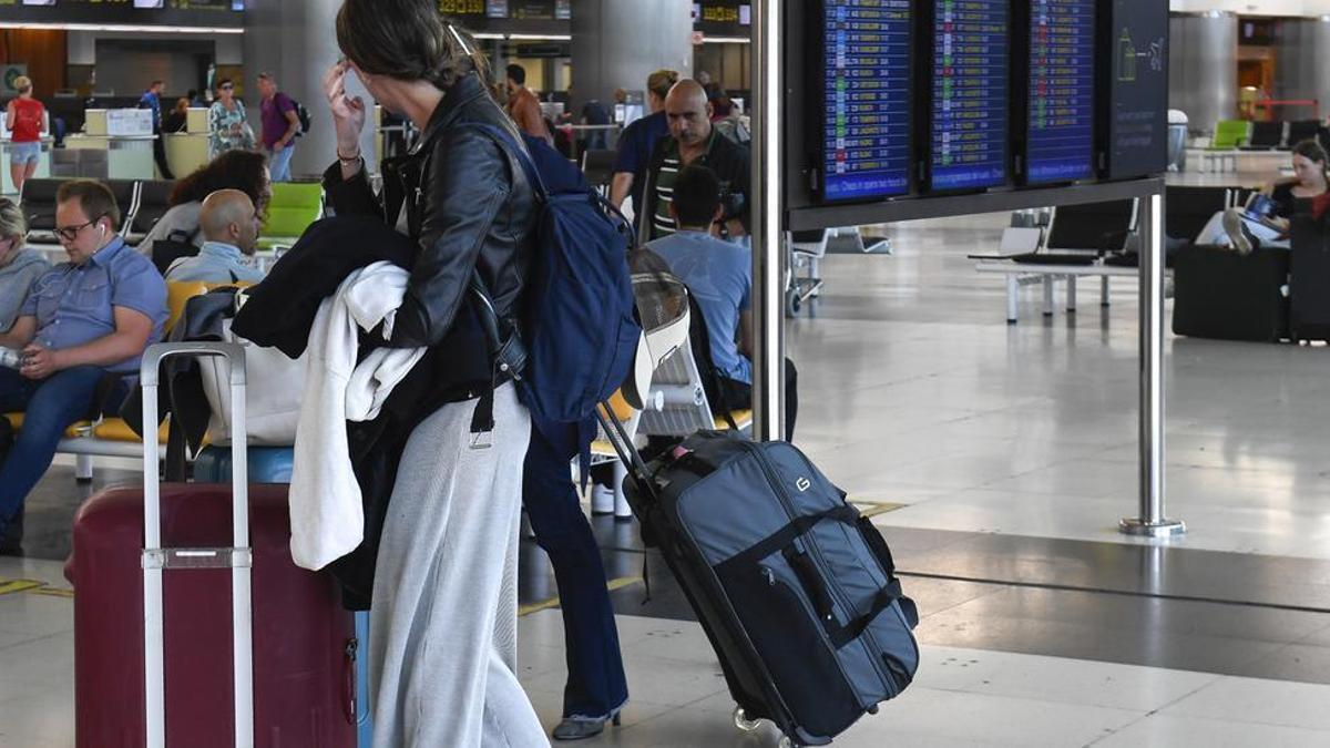 Una pasajera en el aeropuerto junto a sus maletas.