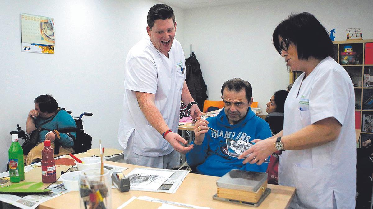 Unos trabajadores sociales junto a una persona con discapacidad intelectual.