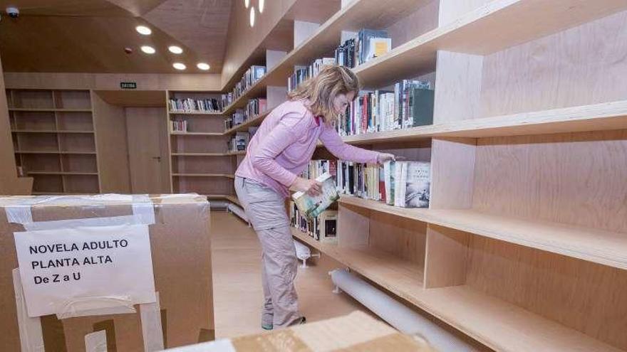 La bibliotecaria, Cristina Vilar, coloca libros en las nuevas estanterías de la sala. // Cristina Graña