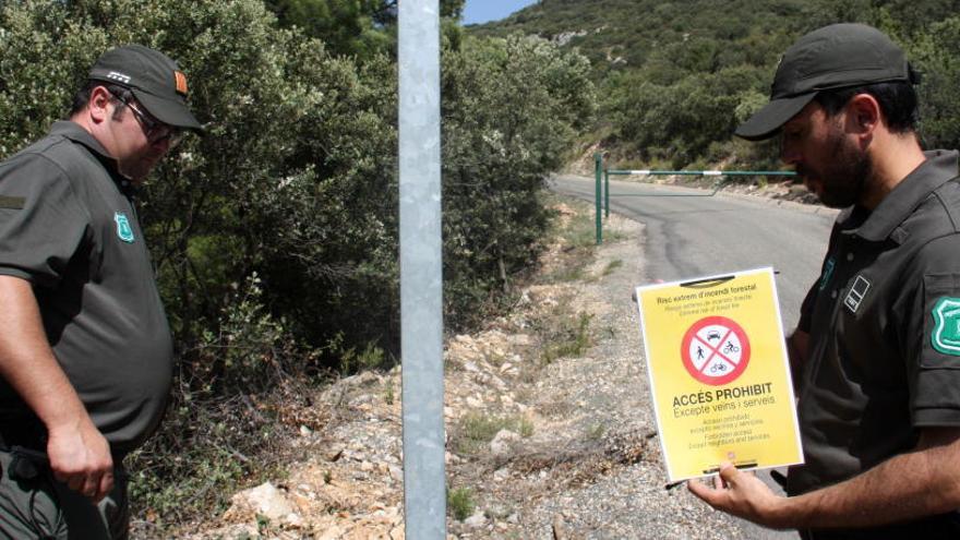 Dos efectius dels Agents Rurals a punt de col·locar un cartell que indica que està prohibit accedir a la serra del Montsec