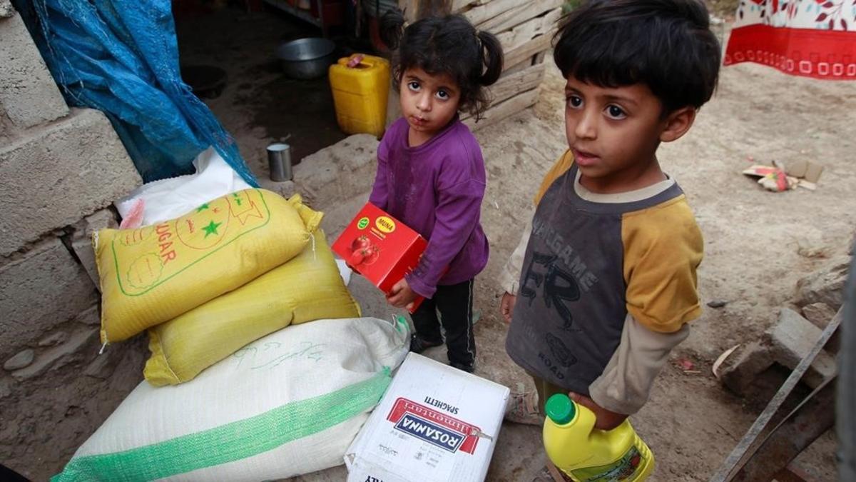 Dos niños yemenís junto a raciones de comida distribuidas por una organización benéfica local, el 15 de junio, en Saná.