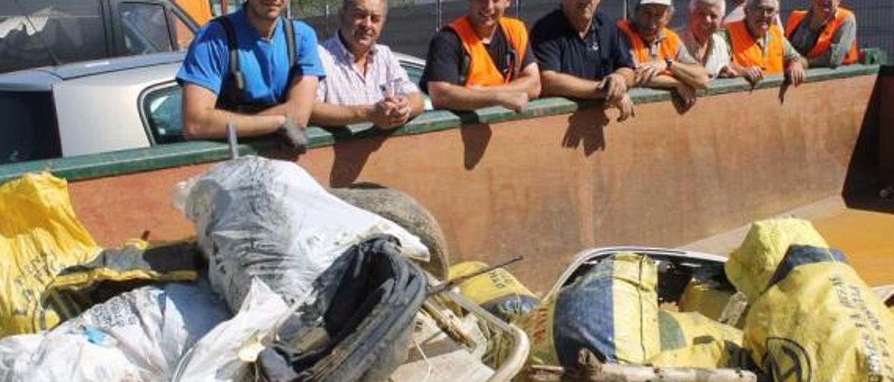 Por la izquierda, Iván García, Luis Miguel Arias, Heber Arenas, Emilio Sánchez, Jovino García, José Camuño, Gil Rico, José García y Joaquín Alperi, parte de los voluntarios que participaron en la limpieza, ayer, en Trevías, ante la basura retirada del Esva.