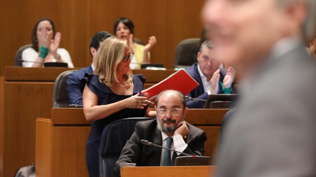 En primer plano, Jorge Azcón se dirige a la tribuna tras la intervención de la portavoz socialista Mayte Pérez, ante la mirada de Javier Lambán.