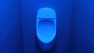 Retrete para hombres en un lavabo con luz azul.