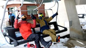 Dos esquiadores suben a un telesilla en la estación de esquí de Baqueira-Beret, ante la mirada de un trabajador de las pistas.