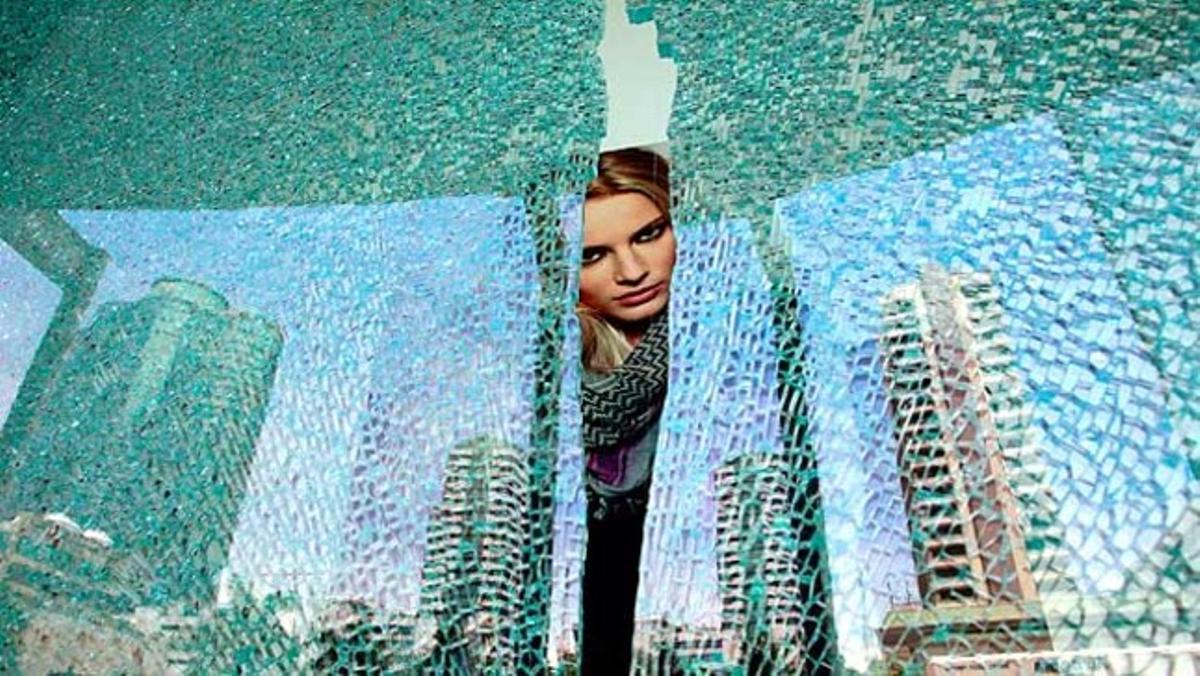 Un cartell publicitari es distingeix a través d¿una finestra trencada al centre de Bangkok (Tailàndia).