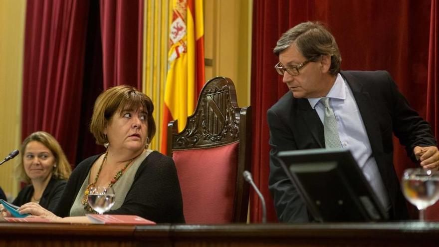 Huertas habla con Thomàs (PSOE) bajo la mirada de Salom (PP) en un pleno del Parlament.