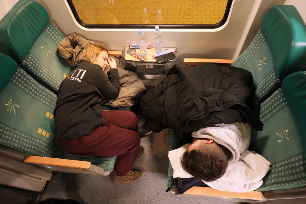 Refugiados ucranianos, dormidos en sus asientos, a su llegada a la estación de tren de Varsovia Este, en Polonia.