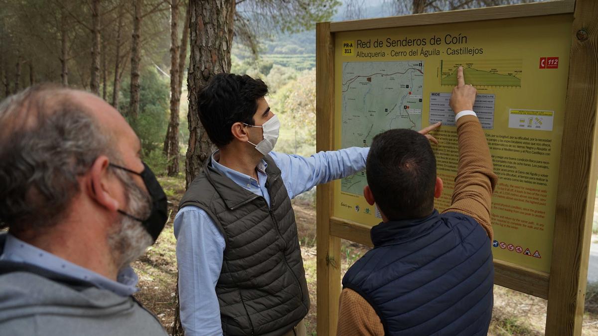 El alcalde de Coín, Francisco Santos, examina la información de uno de los carteles del sendero.