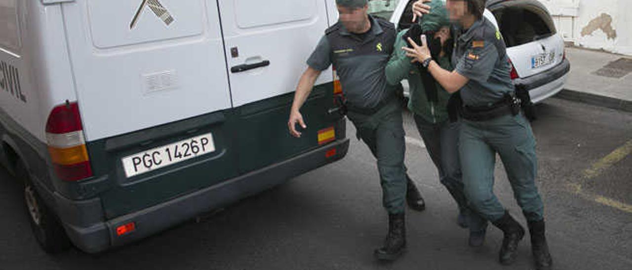 Dos agentes de la Guardia Civil conducen hasta el Juzgado a uno de sus compañeros detenidos, ayer.