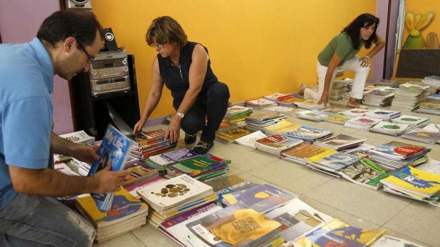 Varios voluntarios organizan los libros en un banco de un APA gallega.