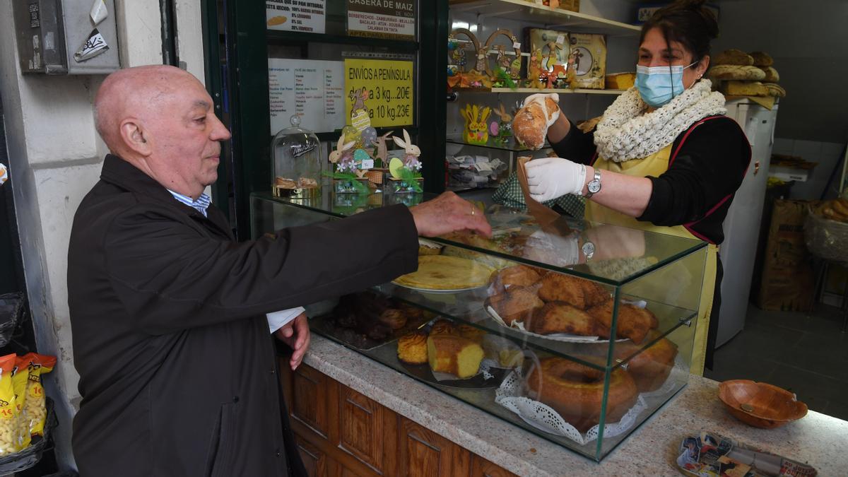 La panadera Sonia Lema entrega una barra de pan a un clientes sin mascarilla.