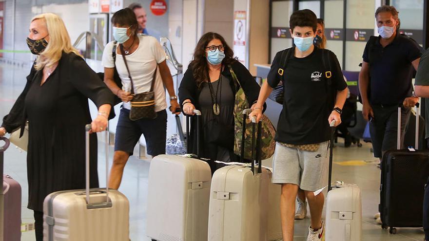 Los turistas llegan al aeropuerto de Ibiza cubiertos con mascarillas.