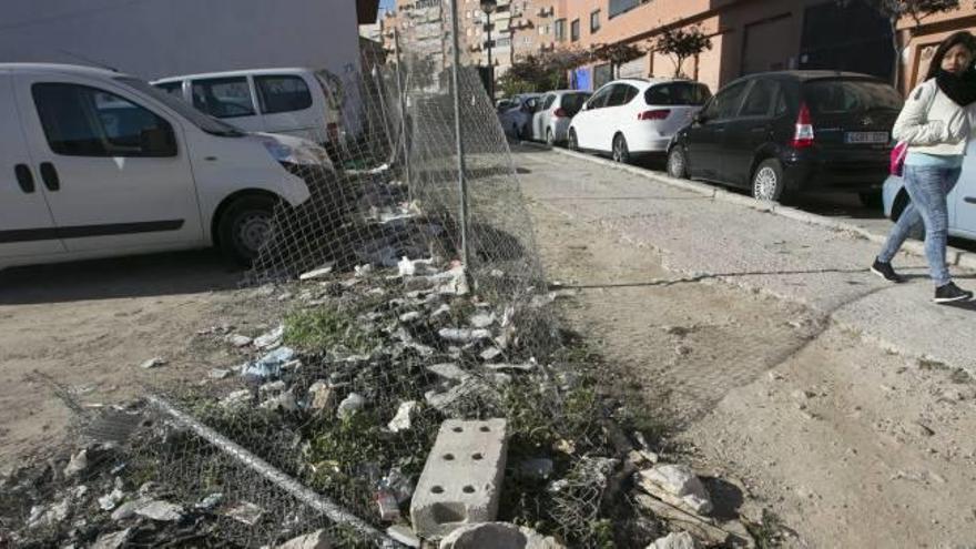 Una valla derribada da acceso a un solar lleno de desperdicios en la calle Llinares