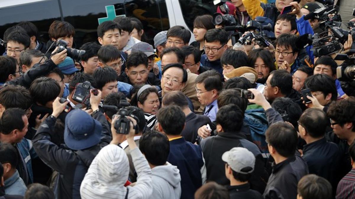 El ministro surcoreano Lee Ju-young, en el centro de la imagen, con gafas, es increpado por familiares de los pasajeros del 'Sewol'