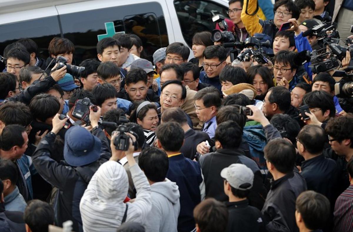 El ministre sud-coreà Lee Ju-young, al centre de la imatge, amb ulleres, és increpat per familiars dels passatgers del ’Sewol’.
