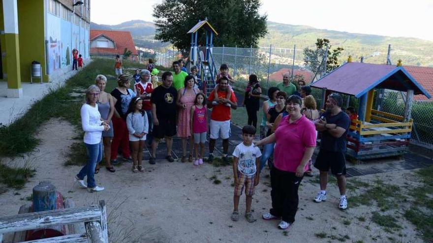 Padres y la directora, con varios niños, en el parque del colegio.