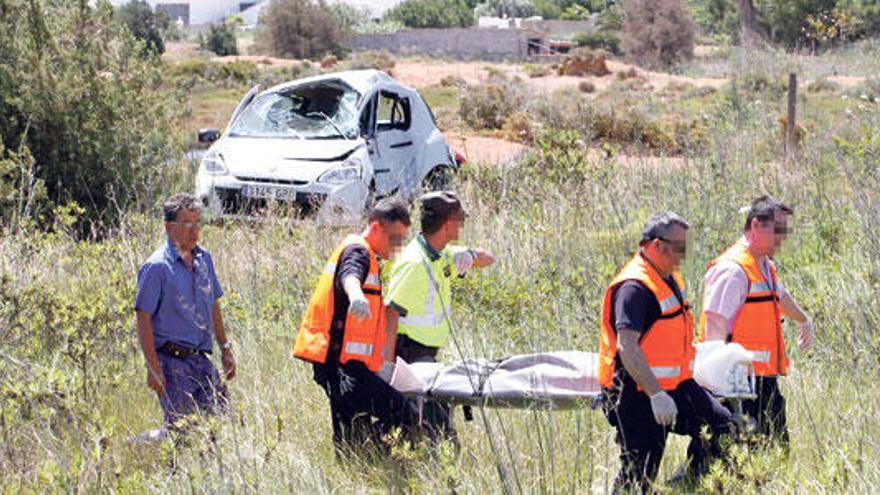 Guardias civiles y sanitarios trasladan el cadáver de la mujer. Al fondo, el coche que conducía.