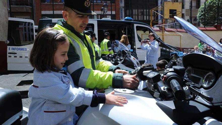 Una niña en una moto de la Guardia Civil. A la izquierda, un agente da explicaciones en el patio del colegio.