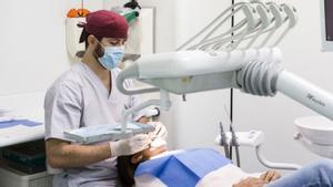 Un dentista atenent una pacient a la seva consulta. | A. NAVARRO / EUROPA PRESS