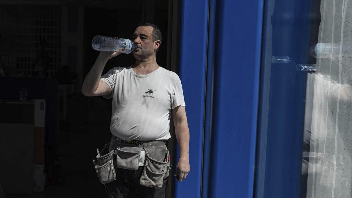 Un treballador de l’empresa de construcció Tabicmon descansa i beu aigua durant la jornada laboral.