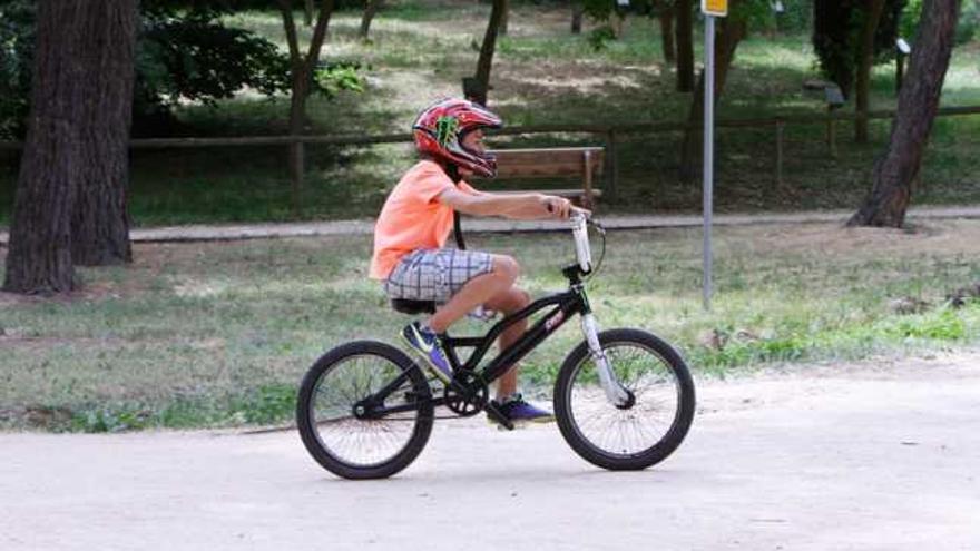 Un menor pasea en bicicleta con el casco puesto.