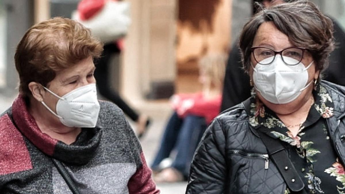 Dos mujeres pasean portando sus mascarillas.