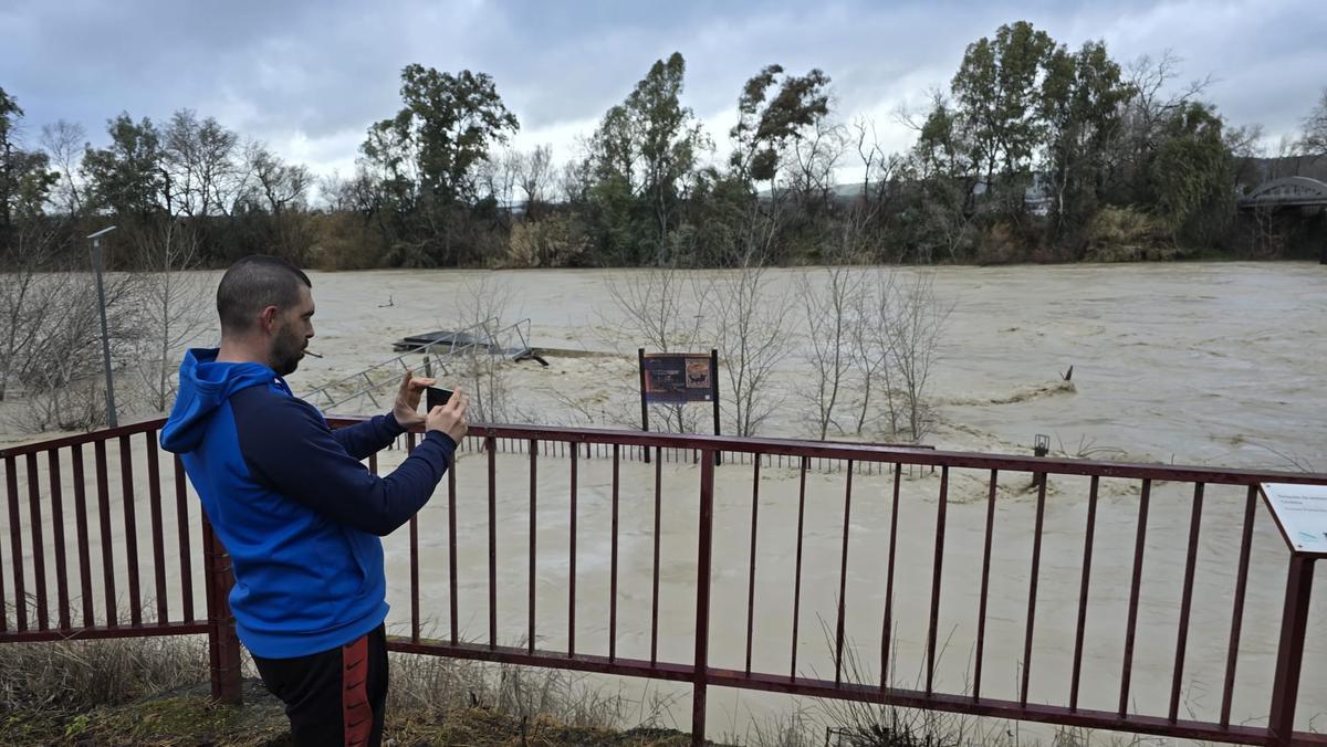 Un vecino fotografía el río Guadalquivir a su paso por Villafranca, este jueves.