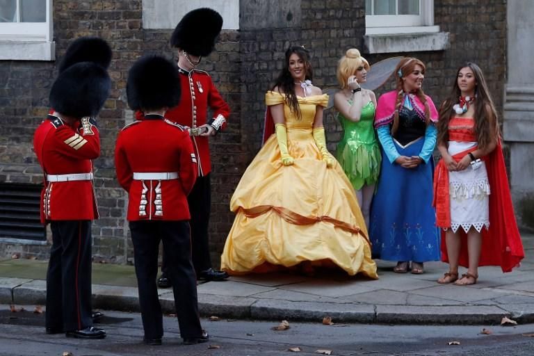 Miembros de la Guardia Real británica junto a un grupo de mujeres vestidas de personajes de Disney, llegadas para un evento en Downing Street, en Londres. - 17 de diciembre de 2018. Adrian DENNIS / AFP