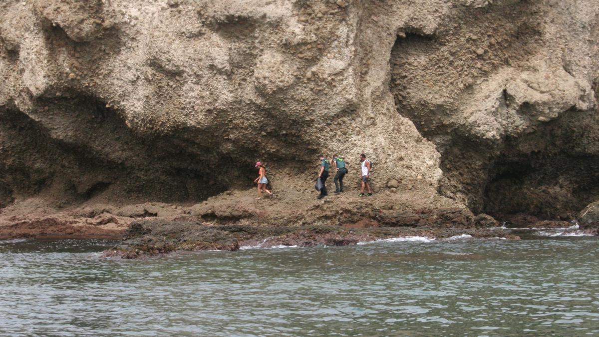 La Guardia Civil portaba en una bolsa de plástico negra los paquetes de lo que podría ser un alijo de hachís que encontraron los dos bañistas que les acompañaban, este sábado.