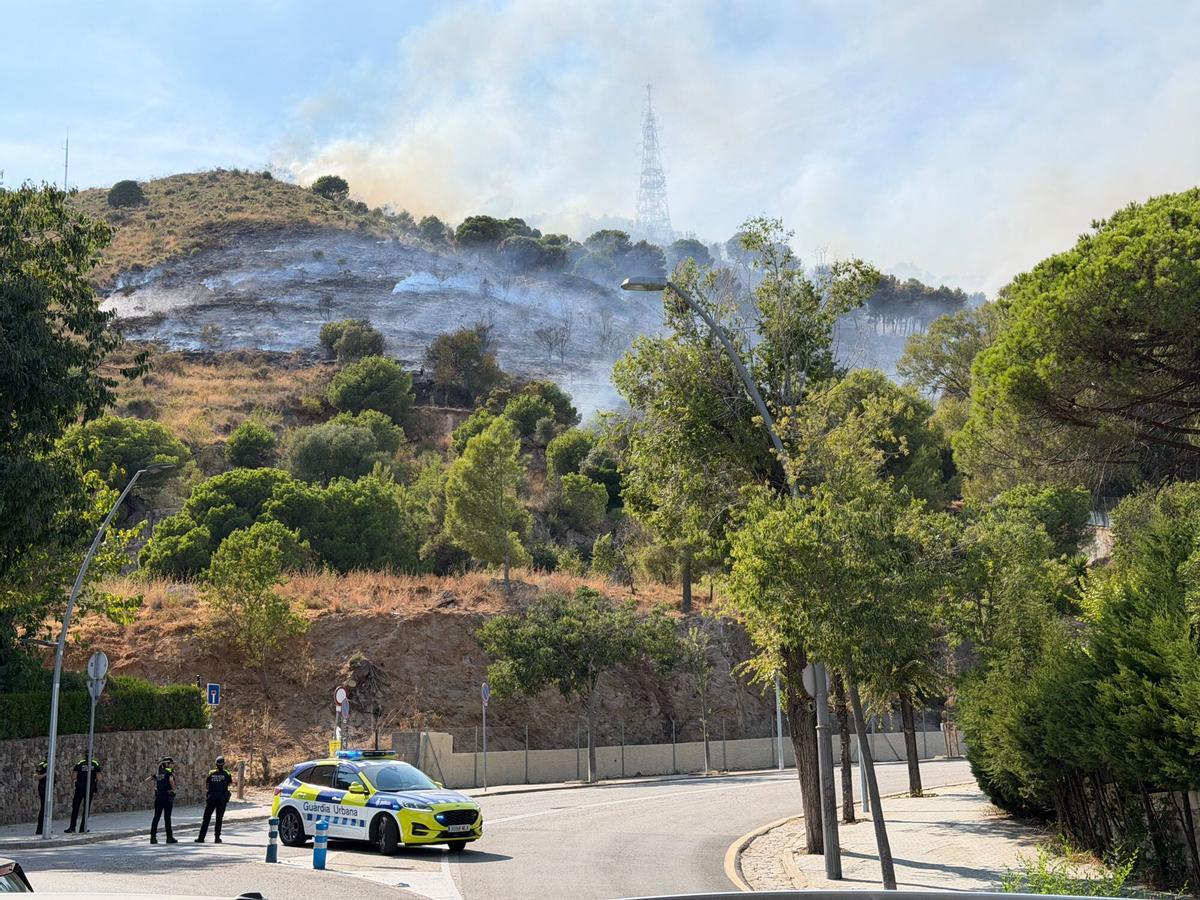 Imagen del incendio en Collserola, con un coche de la Guardia Urbana bloqueando el paso. Imagen del incendio en Collserola, con un coche de la Guardia Urbana bloqueando el paso.