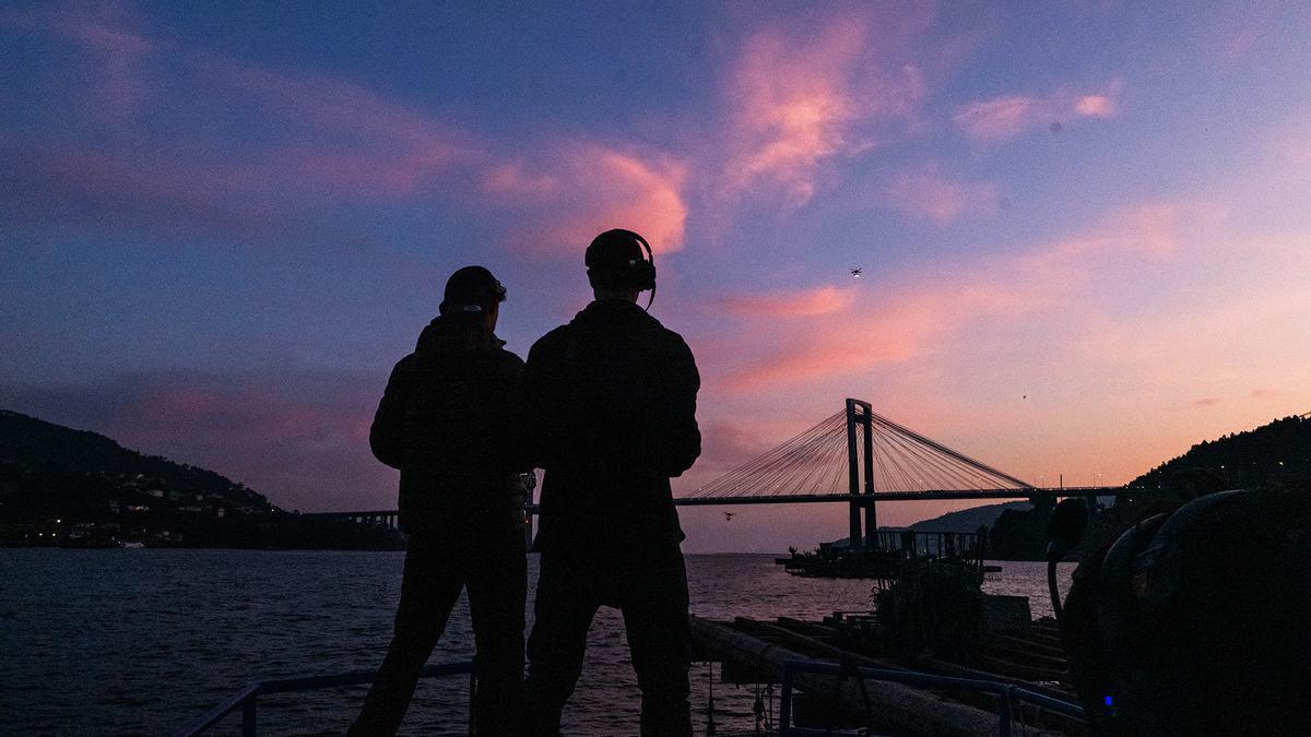 Tangana, junto a compañeros de grabación, contempla desde una batea el puente de Rande.