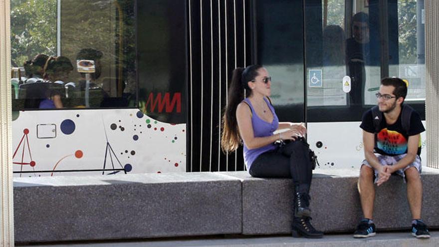 Dos jóvenes, en la parada de la Línea 1 en la Universidad.