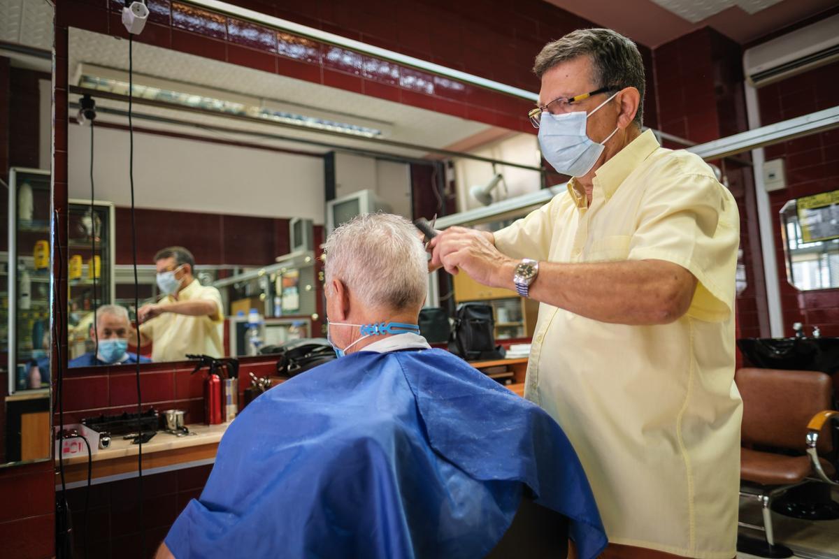 Un peluquero con un cliente en su peluquería.